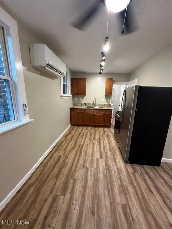 Kitchen with a wealth of natural light, sink, fridge, and wood-type flooring