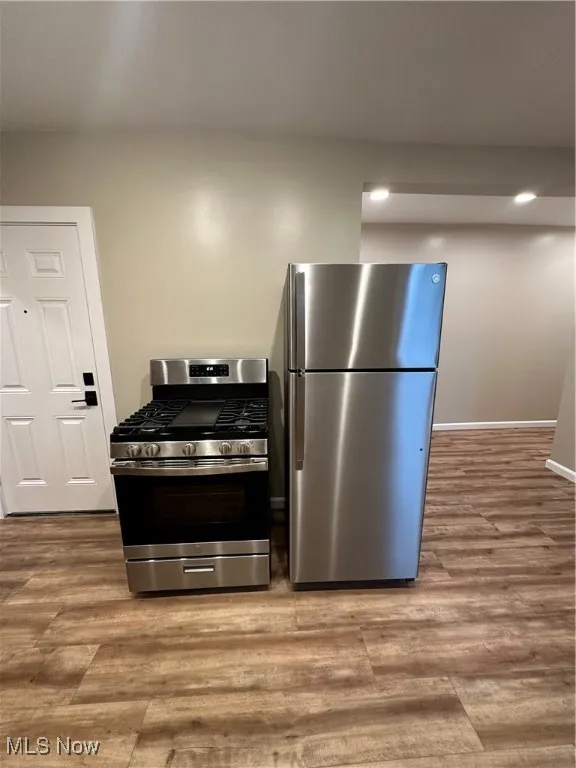 Kitchen featuring light wood-type flooring, stove, and fridge