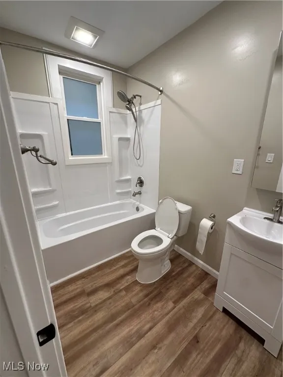 Full bathroom featuring shower / tub combination, toilet, vanity, and wood-type flooring