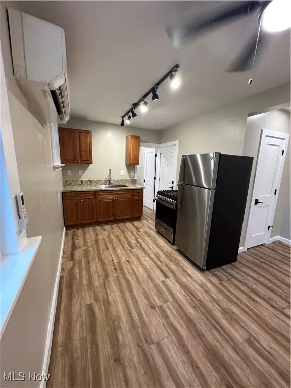 Kitchen with light hardwood / wood-style floors, rail lighting, sink, fridge, and range