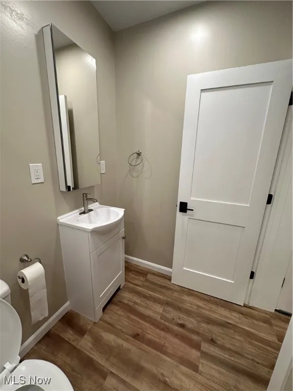 Bathroom featuring wood-type flooring, toilet, and vanity