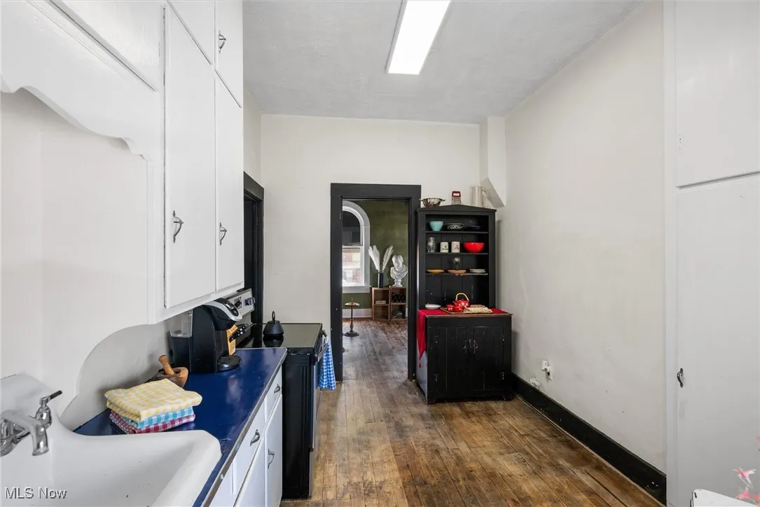 Kitchen with range with electric stovetop, white cabinetry, sink, and dark hardwood / wood-style floors