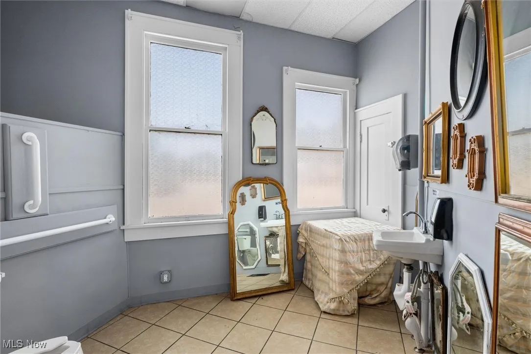 Bathroom with a wealth of natural light, sink, a paneled ceiling, and tile patterned flooring