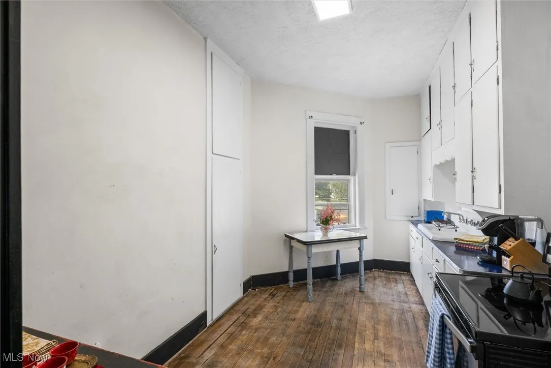 Kitchen with hardwood / wood-style floors, sink, a textured ceiling, double oven range, and white cabinetry
