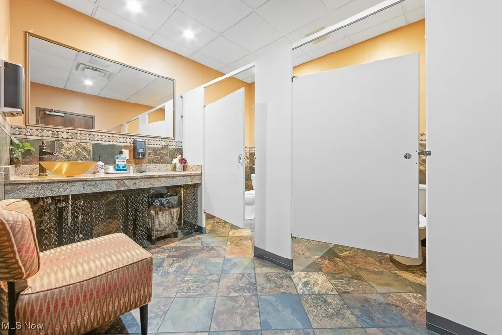 Bathroom with backsplash, tile patterned flooring, toilet, and vanity