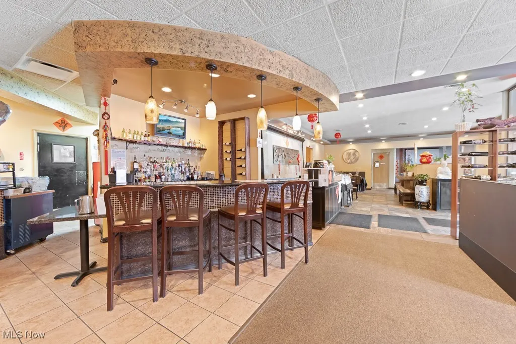Bar with a drop ceiling, decorative light fixtures, and light tile patterned floors