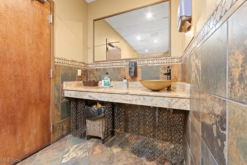 Bathroom featuring tile walls, decorative backsplash, vanity, and tile patterned floors