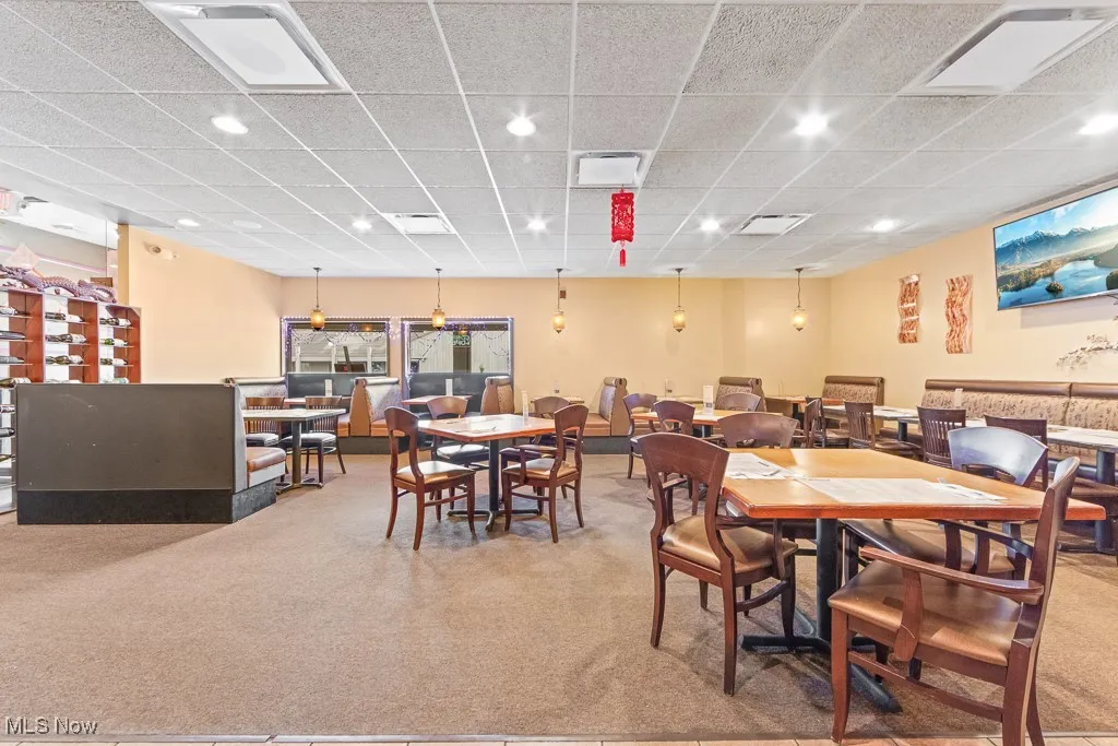 Carpeted dining space featuring a paneled ceiling