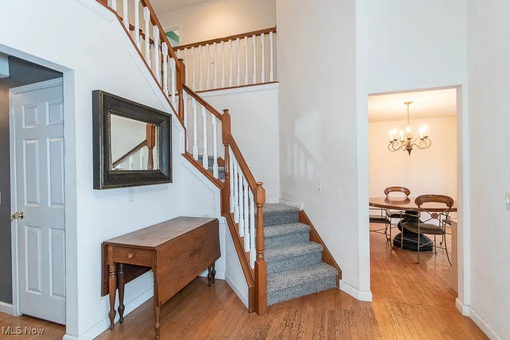 Stairway with hardwood / wood-style floors and an inviting chandelier