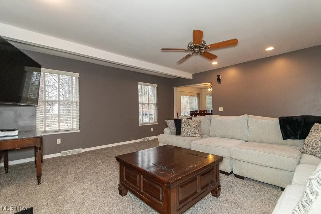 Carpeted living room with ceiling fan