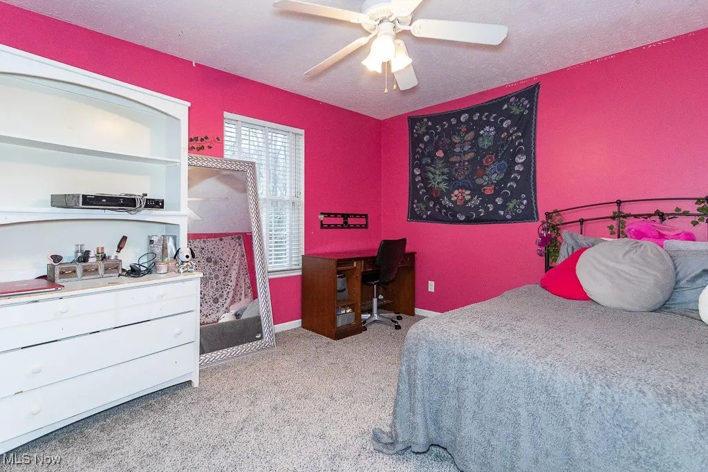 Carpeted bedroom featuring ceiling fan and a textured ceiling