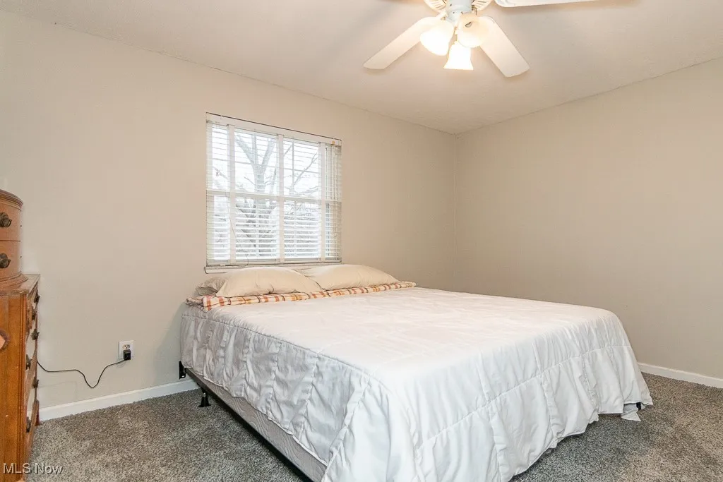 Bedroom with dark carpet and ceiling fan