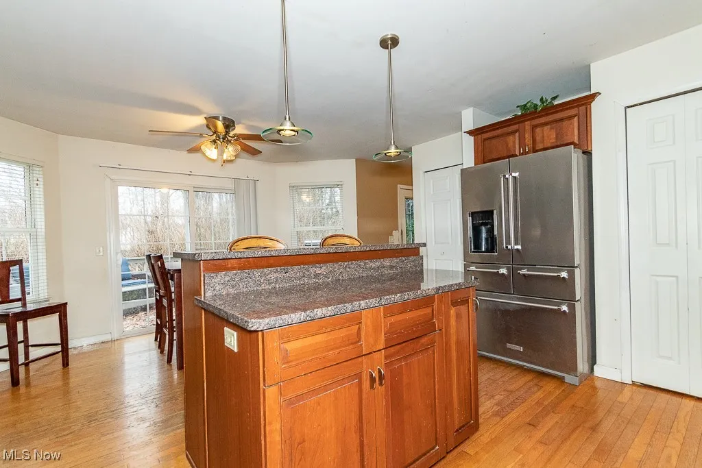 Kitchen featuring light wood-type flooring, a center island, high end fridge, and ceiling fan