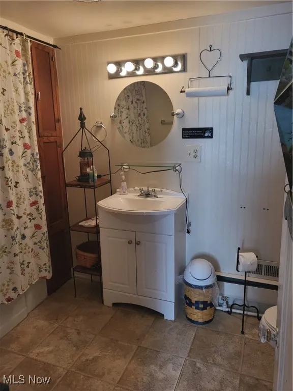 Bathroom featuring vanity, a shower with shower curtain, and wooden walls