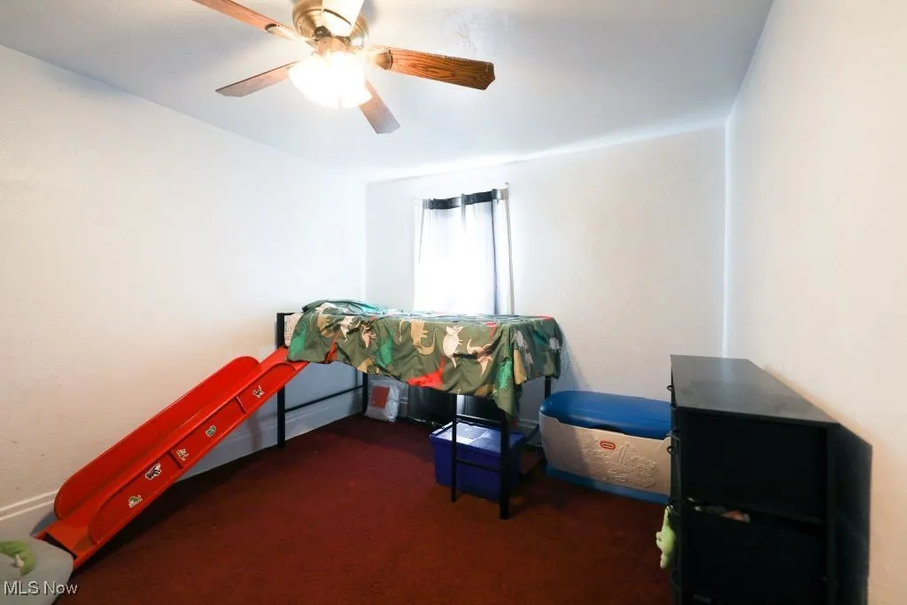 Another view of the carpeted bedroom with ceiling fan.