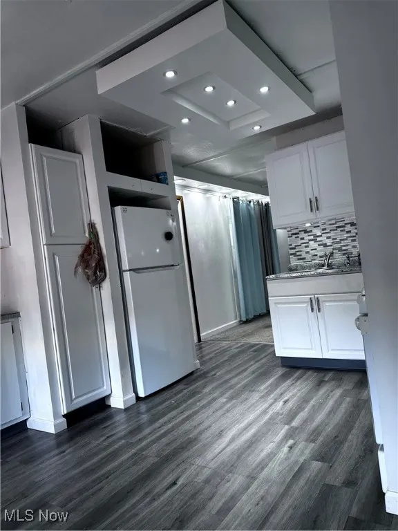 Kitchen with dark hardwood / wood-style flooring, refrigerator, and white cabinets