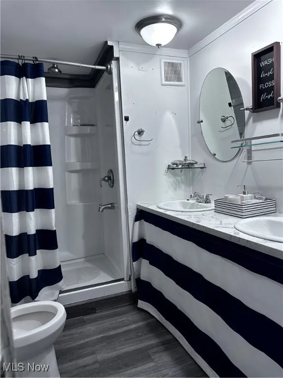Bathroom featuring toilet, crown molding, vanity, wood-type flooring, and a shower with shower curtain