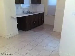 Kitchen with light tile patterned floors, sink, and dark brown cabinetry