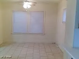 Empty room with light tile patterned flooring and ceiling fan