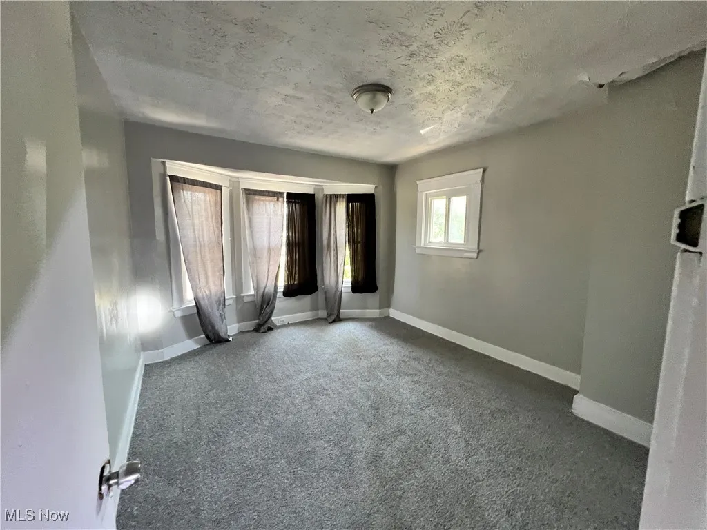 Unfurnished bedroom featuring a textured ceiling and dark colored carpet