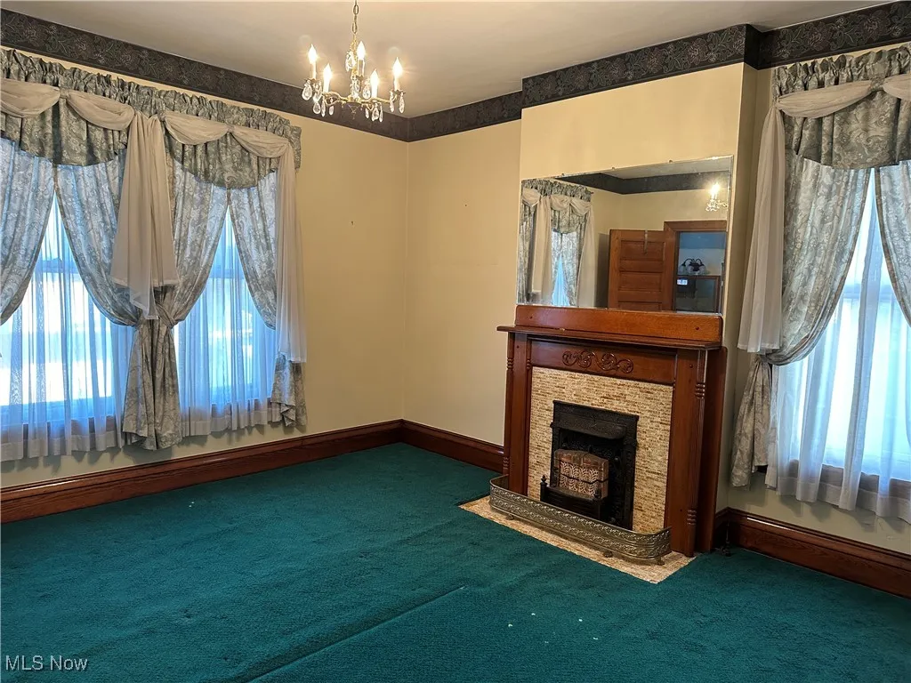 Unfurnished living room featuring a chandelier and dark colored carpet