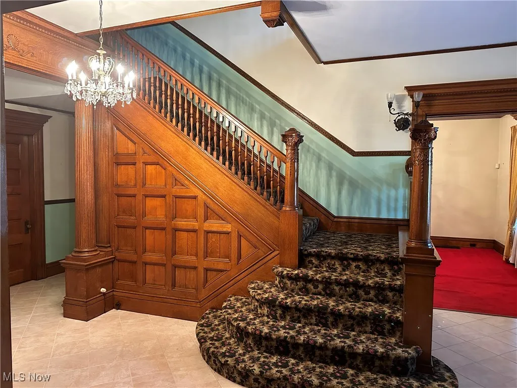 Stairway featuring ornamental molding, tile patterned floors, and a chandelier