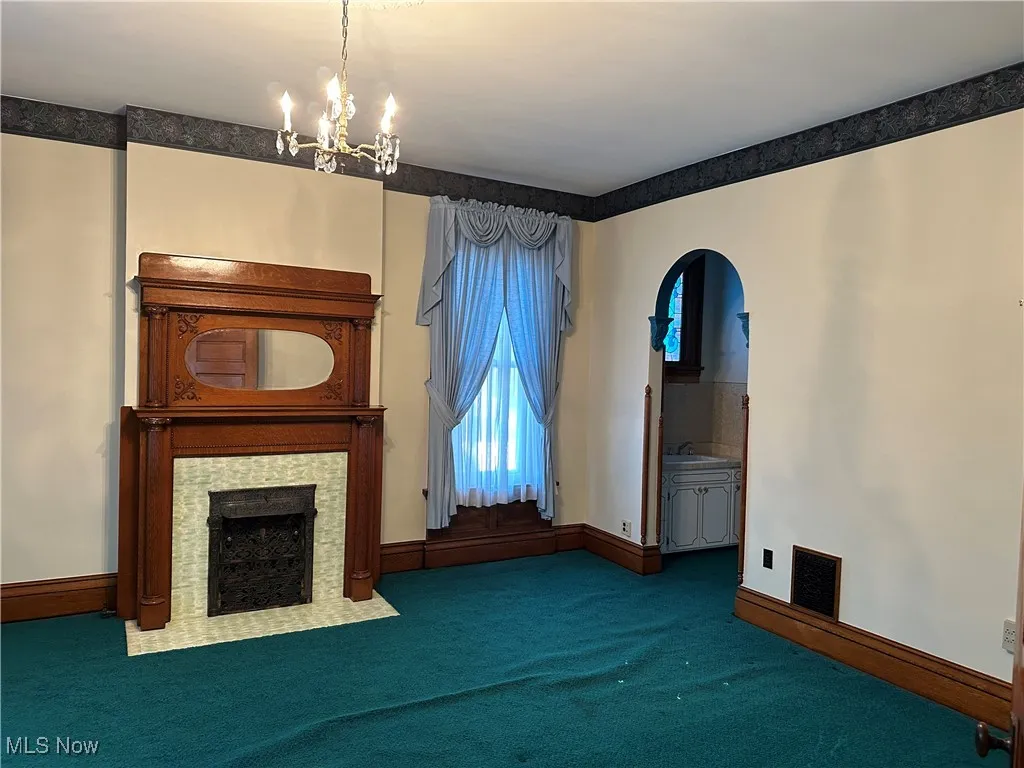 Unfurnished living room with carpet, an inviting chandelier, and sink