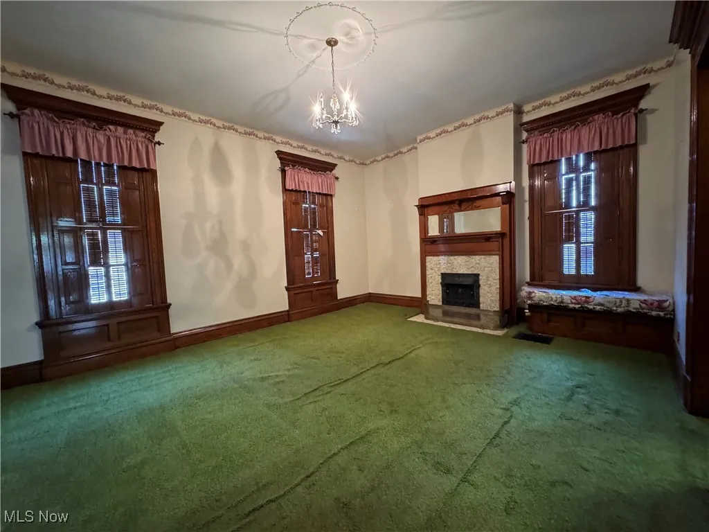Unfurnished living room featuring a notable chandelier and carpet floors