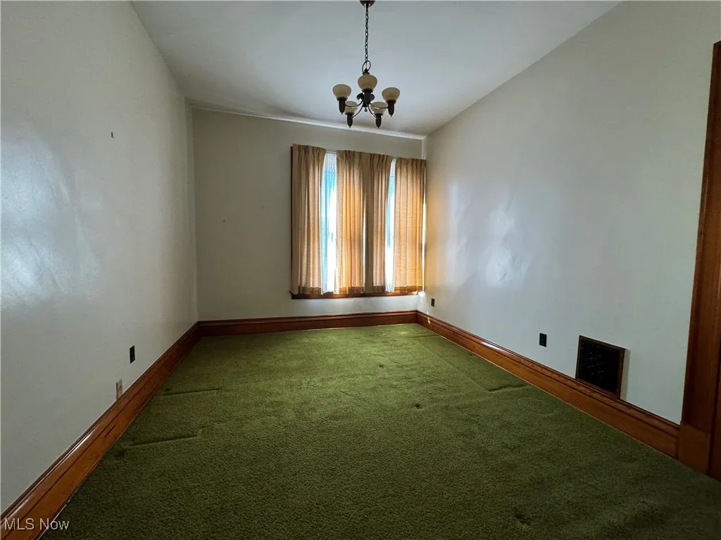 Empty room featuring a notable chandelier and carpet floors