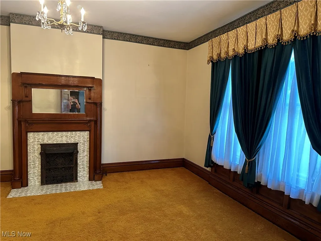 Unfurnished living room with carpet and a chandelier
