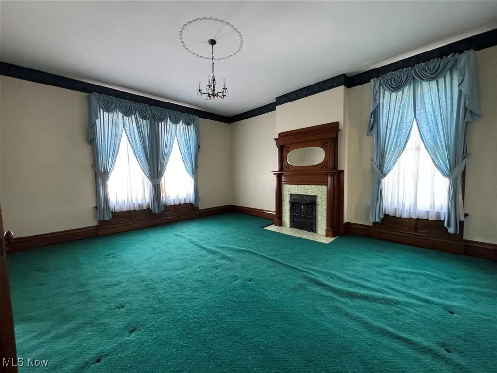Unfurnished living room featuring carpet and an inviting chandelier