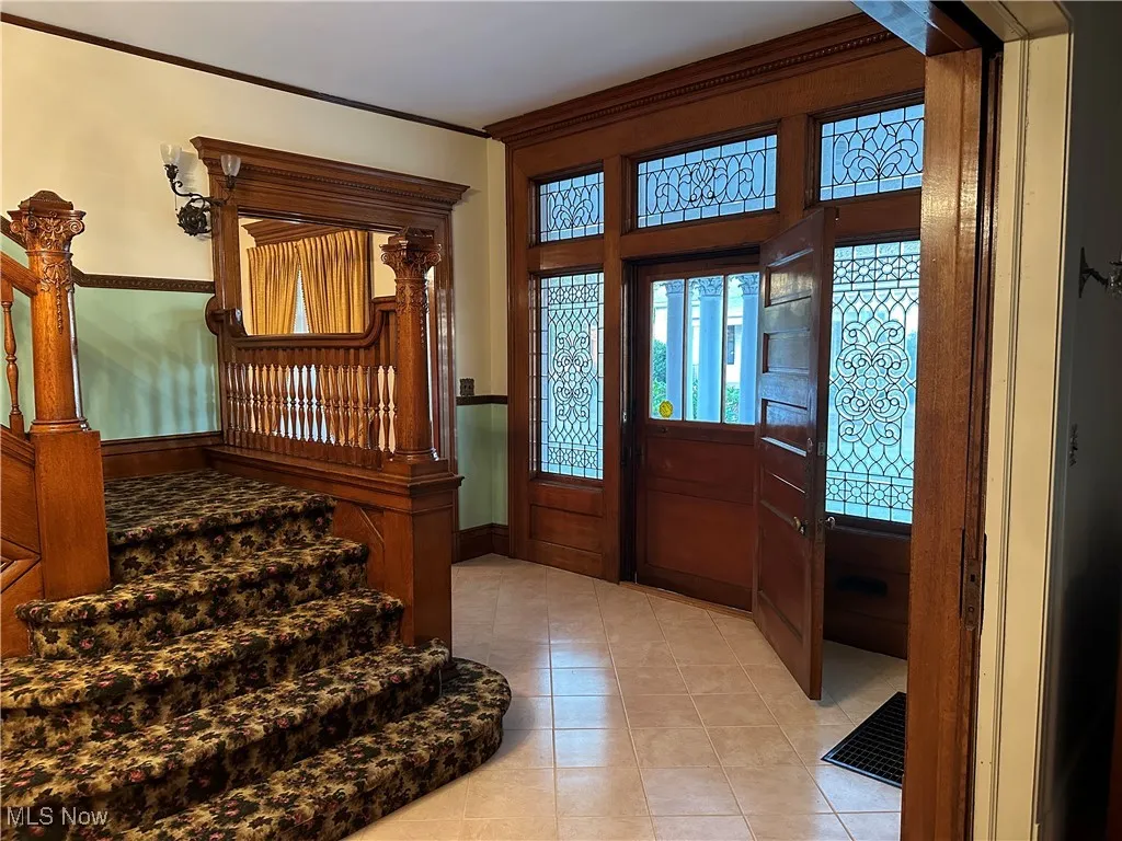 Tiled foyer entrance featuring crown molding