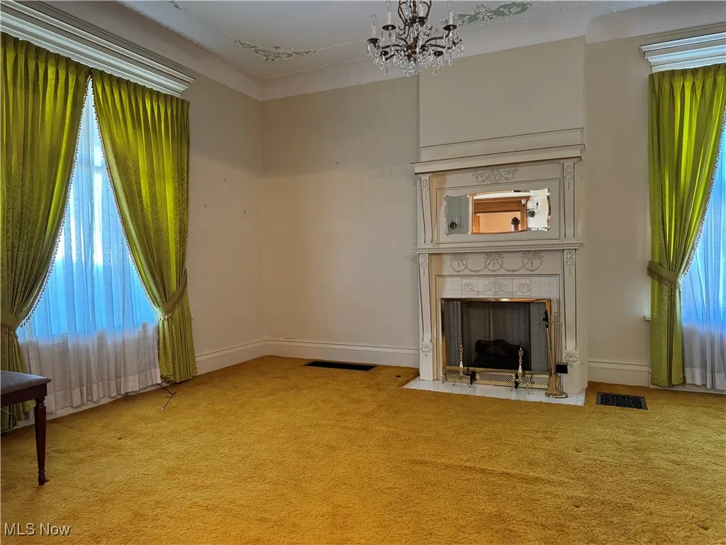 Unfurnished living room featuring light carpet and an inviting chandelier