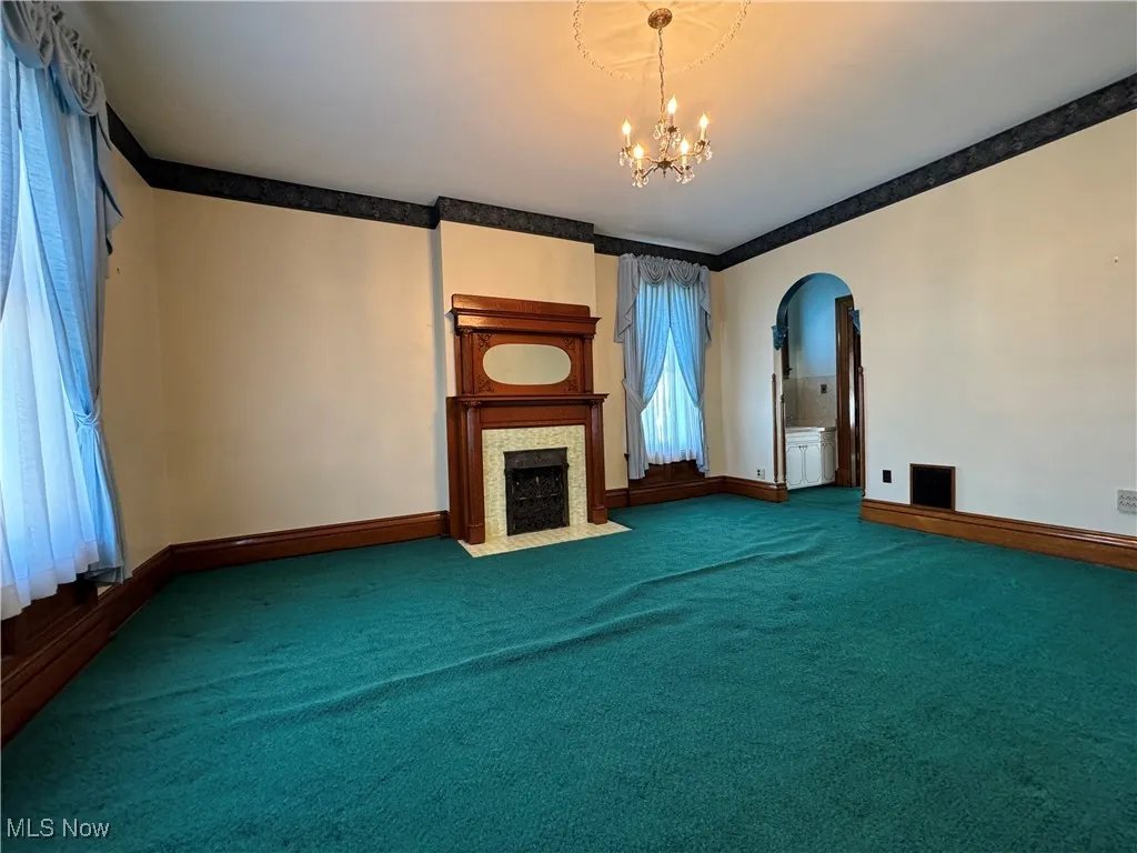 Unfurnished living room featuring a chandelier and carpet