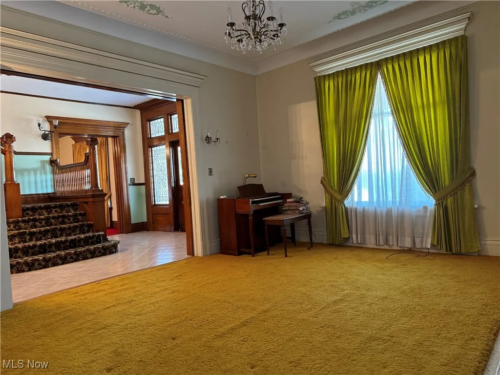 Unfurnished office featuring ornamental molding, a chandelier, and light colored carpet