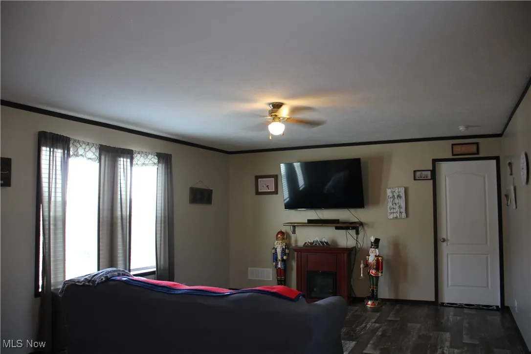Living room featuring ornamental molding, dark hardwood / wood-style flooring, a healthy amount of sunlight, and ceiling fan