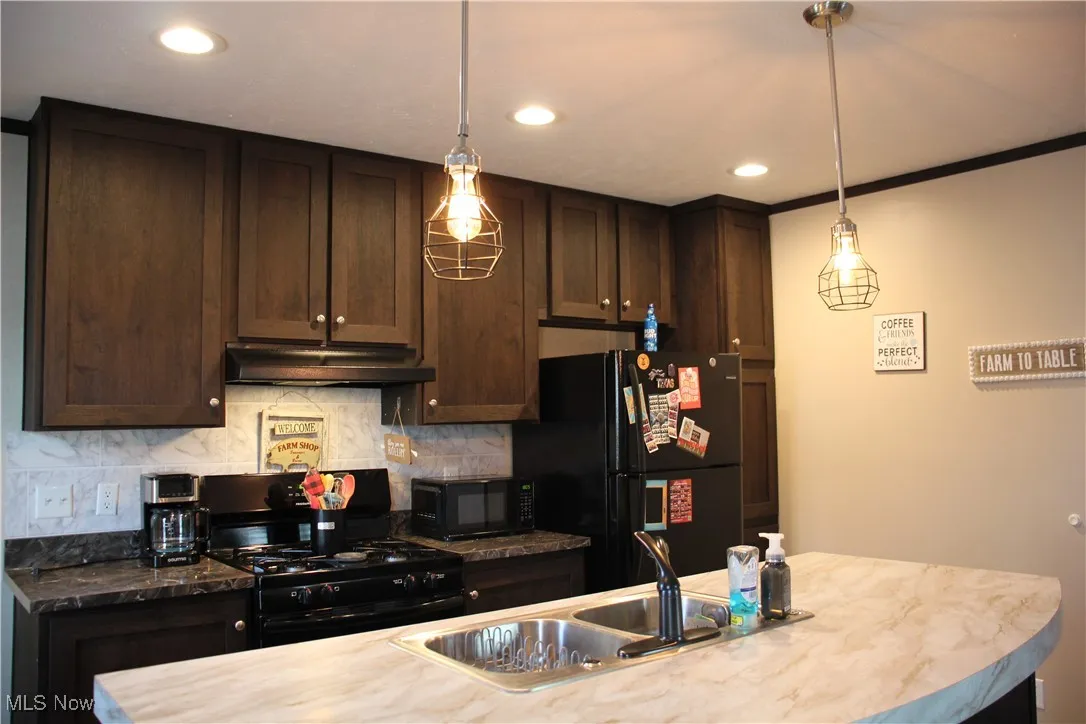 Kitchen featuring crown molding, black appliances, dark brown cabinetry, and tasteful backsplash