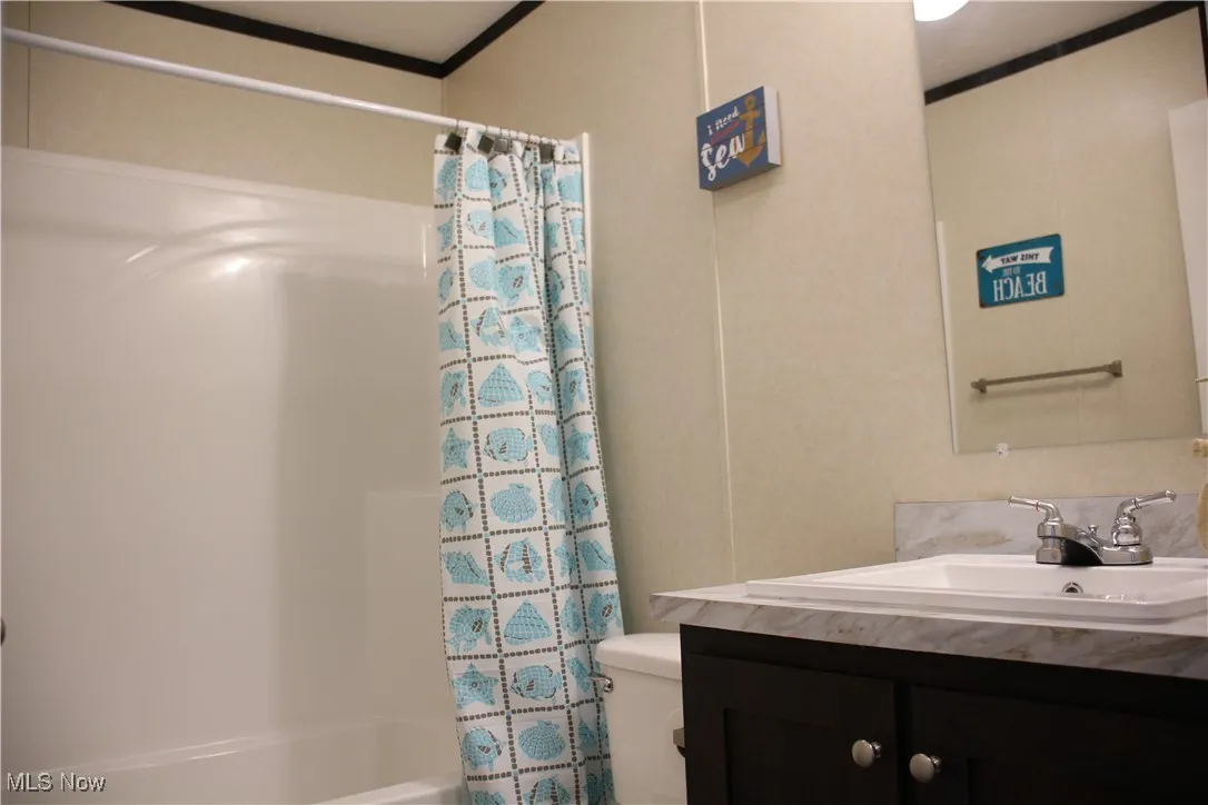 Full bathroom featuring ornamental molding, vanity, toilet, and shower / bath combo with shower curtain
