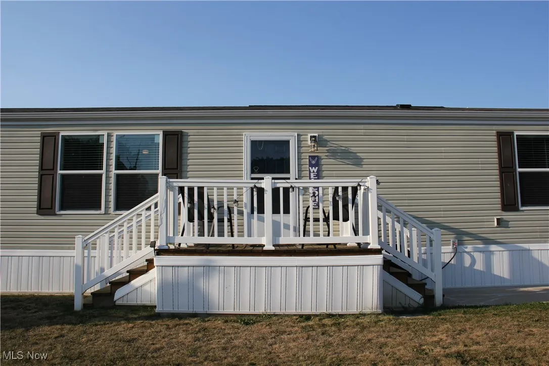 View of exterior entry featuring a yard and a deck