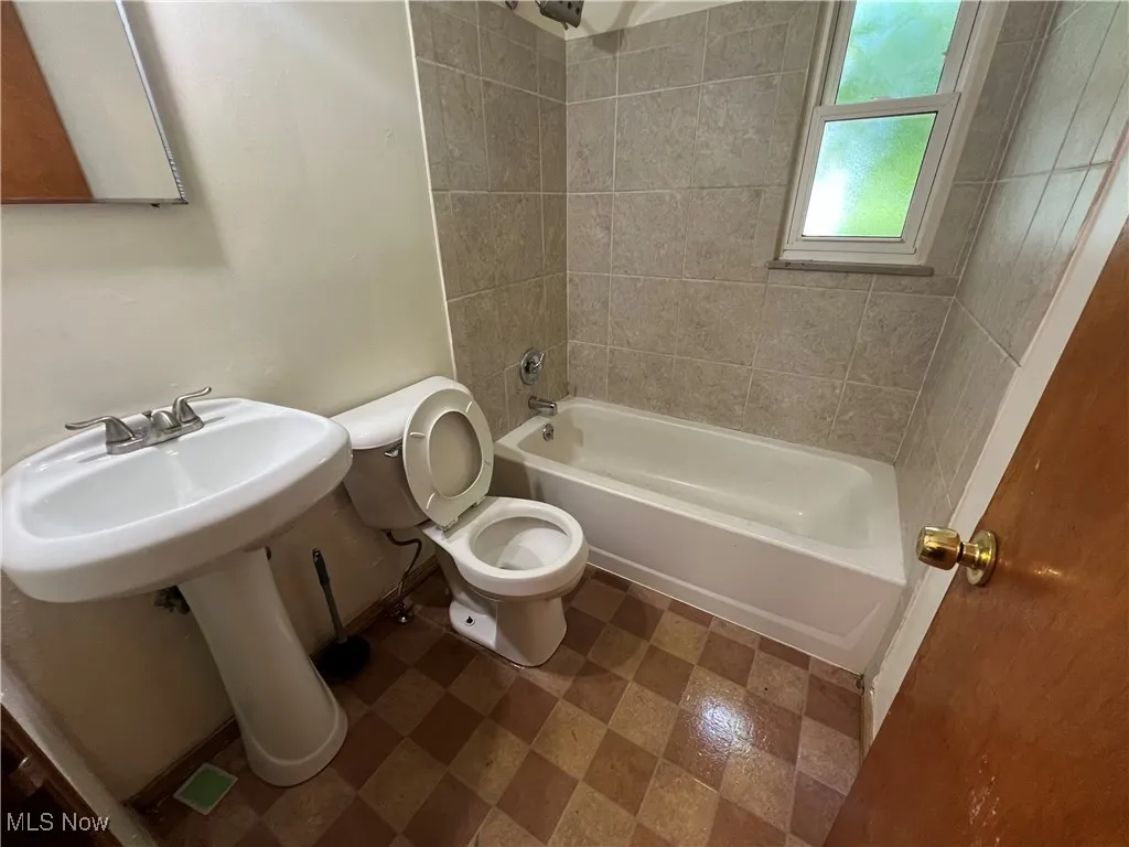 Bathroom with tiled shower / bath combo and toilet