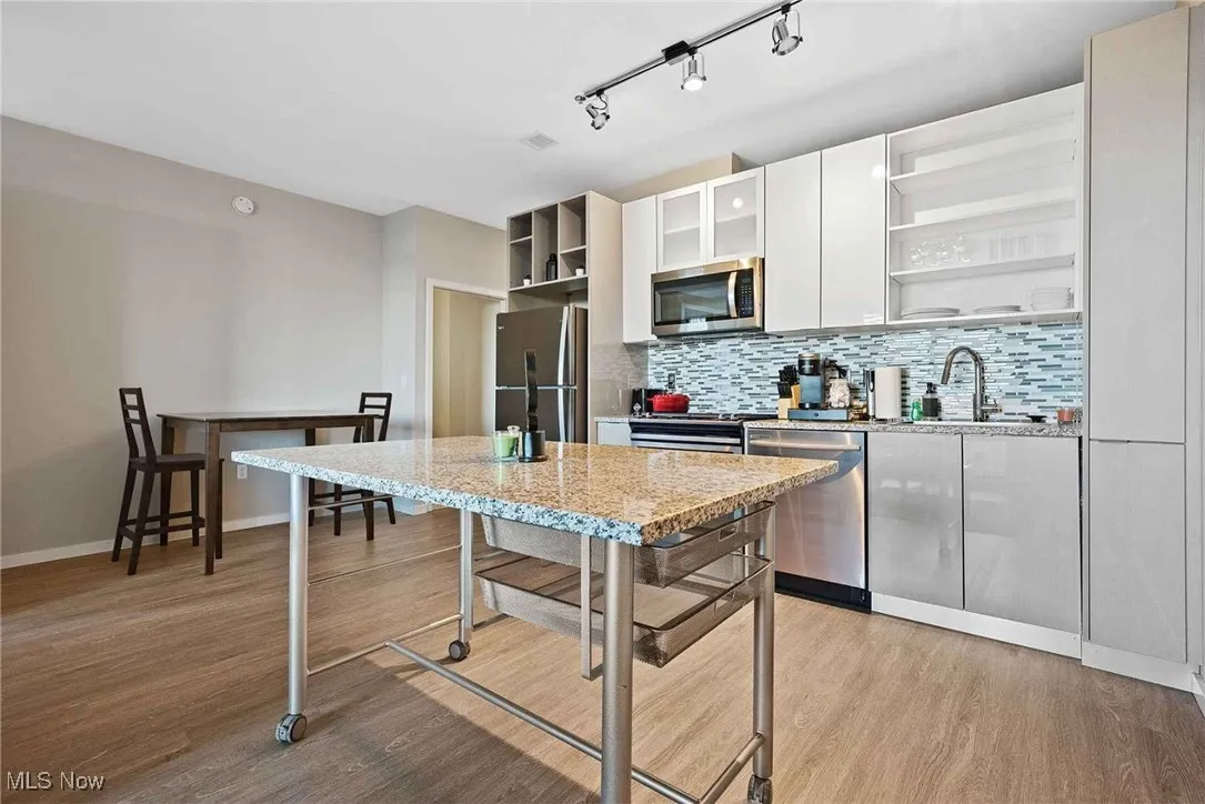 Kitchen featuring light wood-type flooring, stainless steel appliances, and white cabinets