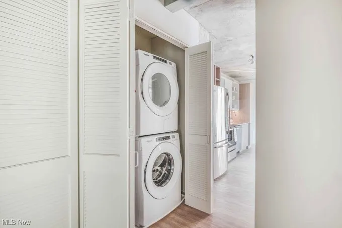 Laundry area featuring stacked washer and clothes dryer and light hardwood / wood-style floors