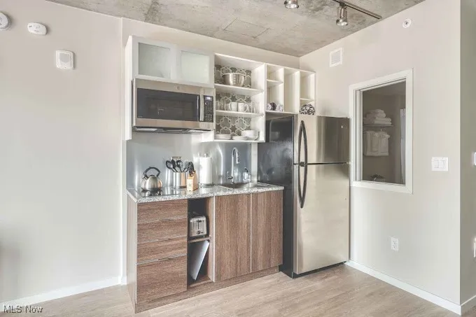 Kitchen with track lighting, stainless steel appliances, sink, and light hardwood / wood-style flooring
