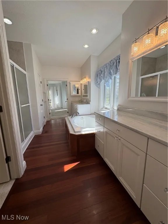 Full bathroom featuring vanity, recessed lighting, wood finished floors, a garden tub, and a stall shower
