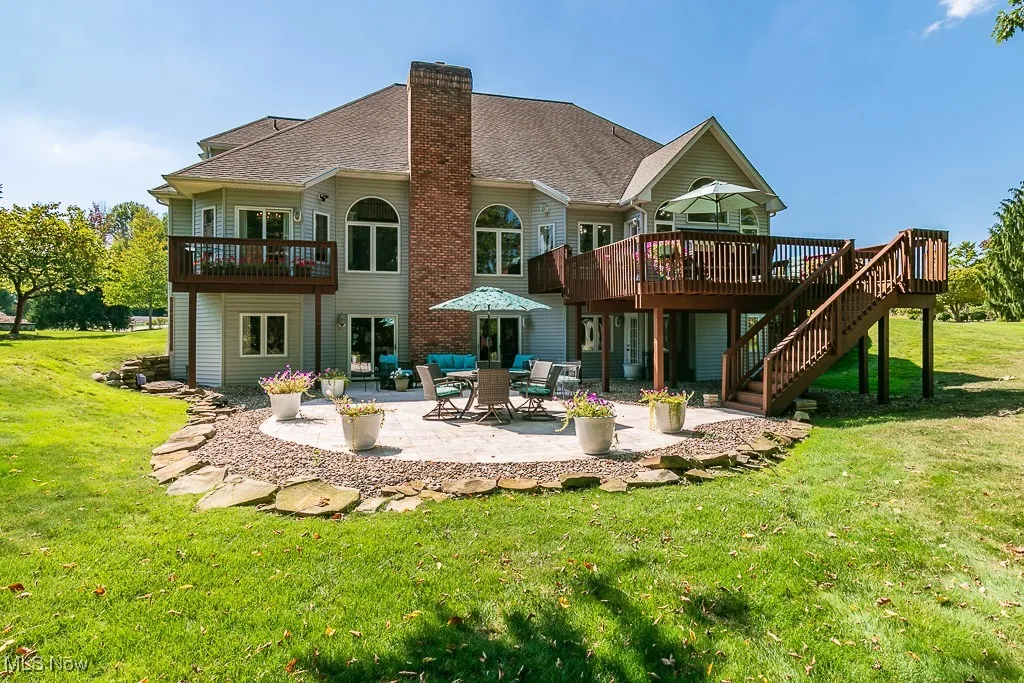 Back of property featuring a deck, a yard, and a patio area