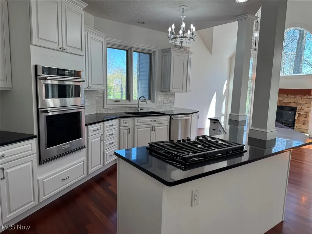 Kitchen featuring decorative backsplash, dark countertops, a sink, stainless steel appliances, and dark wood-type flooring
