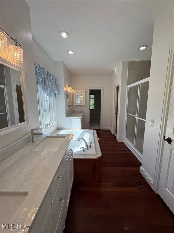 Bathroom with a sink, a stall shower, recessed lighting, and wood finished floors