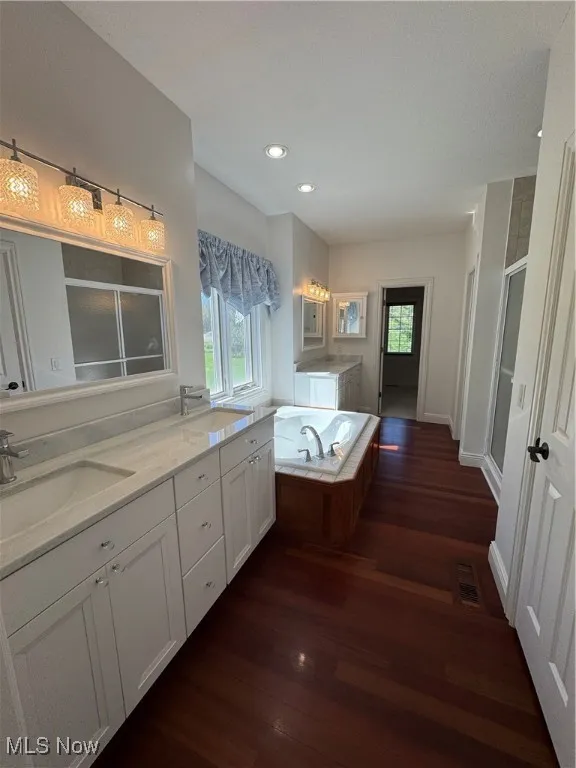 Bathroom featuring a sink, a shower stall, wood finished floors, and plenty of natural light