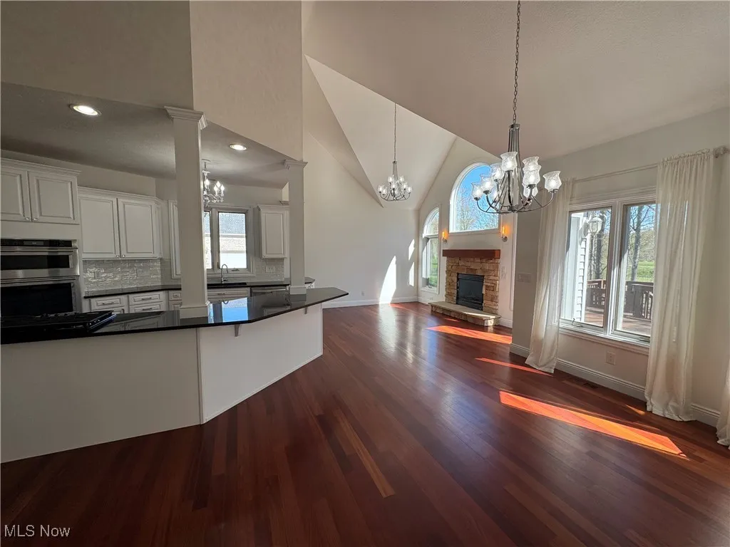 Kitchen featuring dark countertops, dark wood finished floors, double oven, open floor plan, and an inviting chandelier