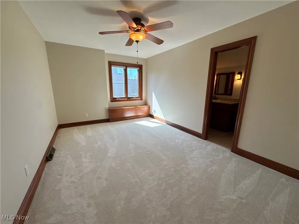 Carpeted empty room with baseboards, ceiling fan, and visible vents